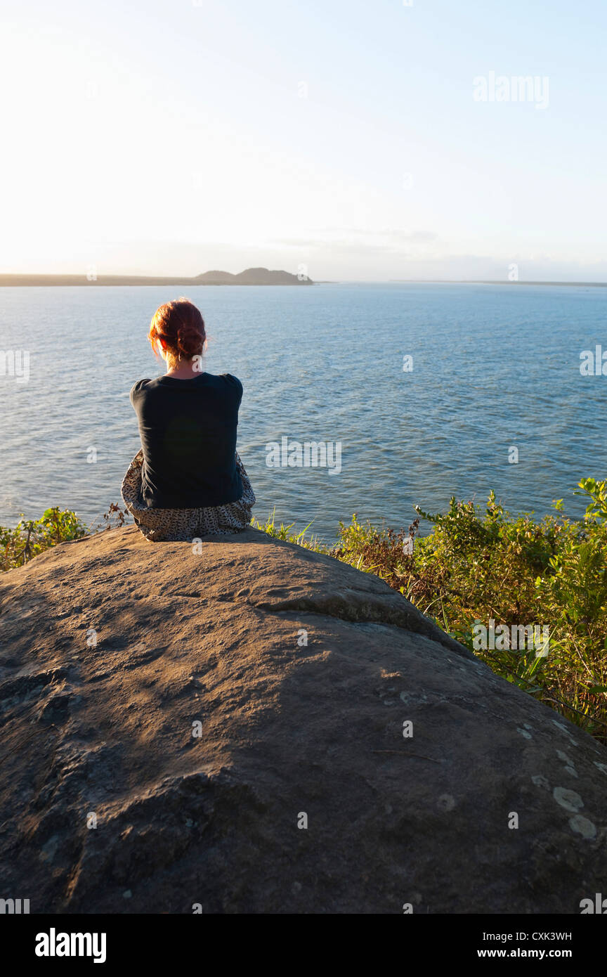 Rückansicht der Frau auf Felsen sitzend, Ilha do Mel, Parana, Brasilien Stockfoto