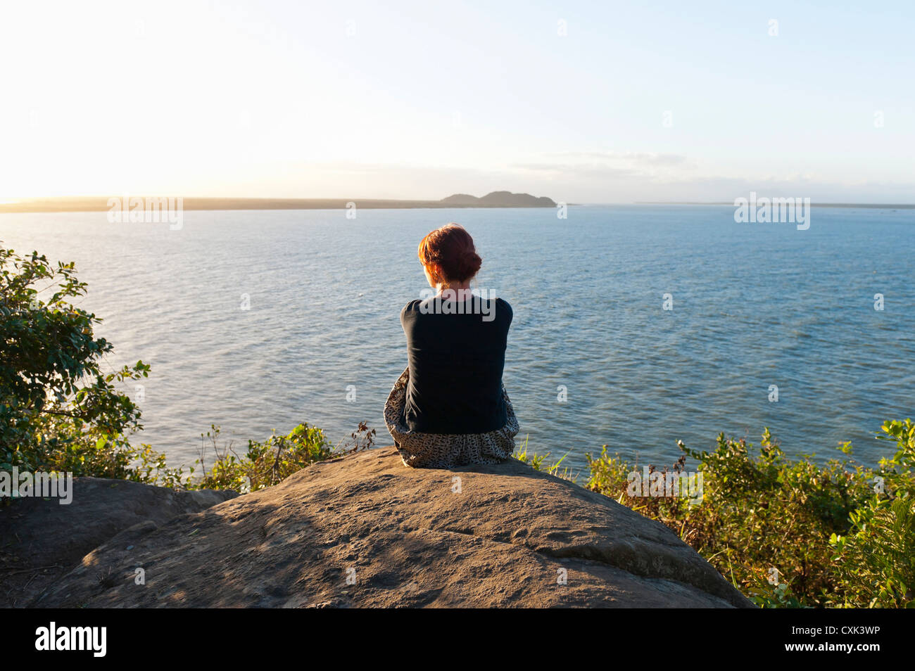 Rückansicht der Frau sitzen auf Hügel, Ilha do Mel, Parana, Brasilien Stockfoto