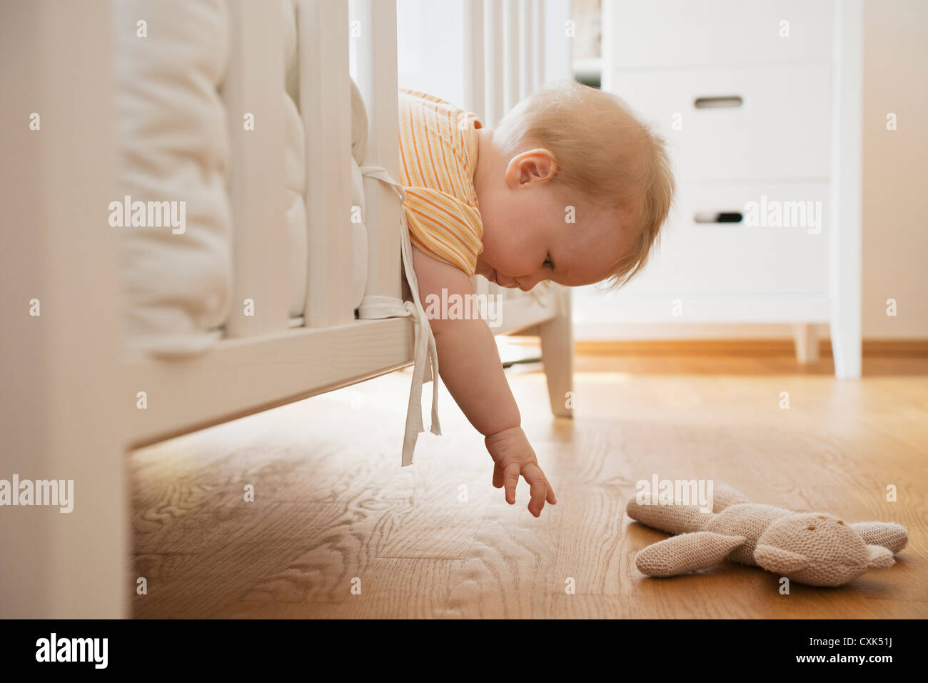 Baby Mädchen aus Krippe gefüllte Spielzeug zu erreichen Stockfoto