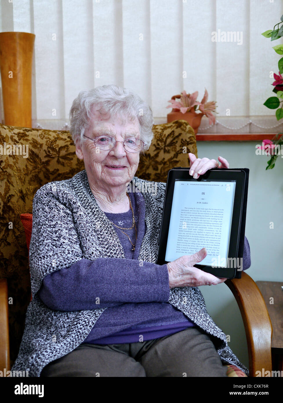 Glücklich und lächelnd 90 Jahre alten neunzigjährigen englische Rentner erfreut eine iPad als ihr Geburtstagsgeschenk erhalten. England-UK Stockfoto
