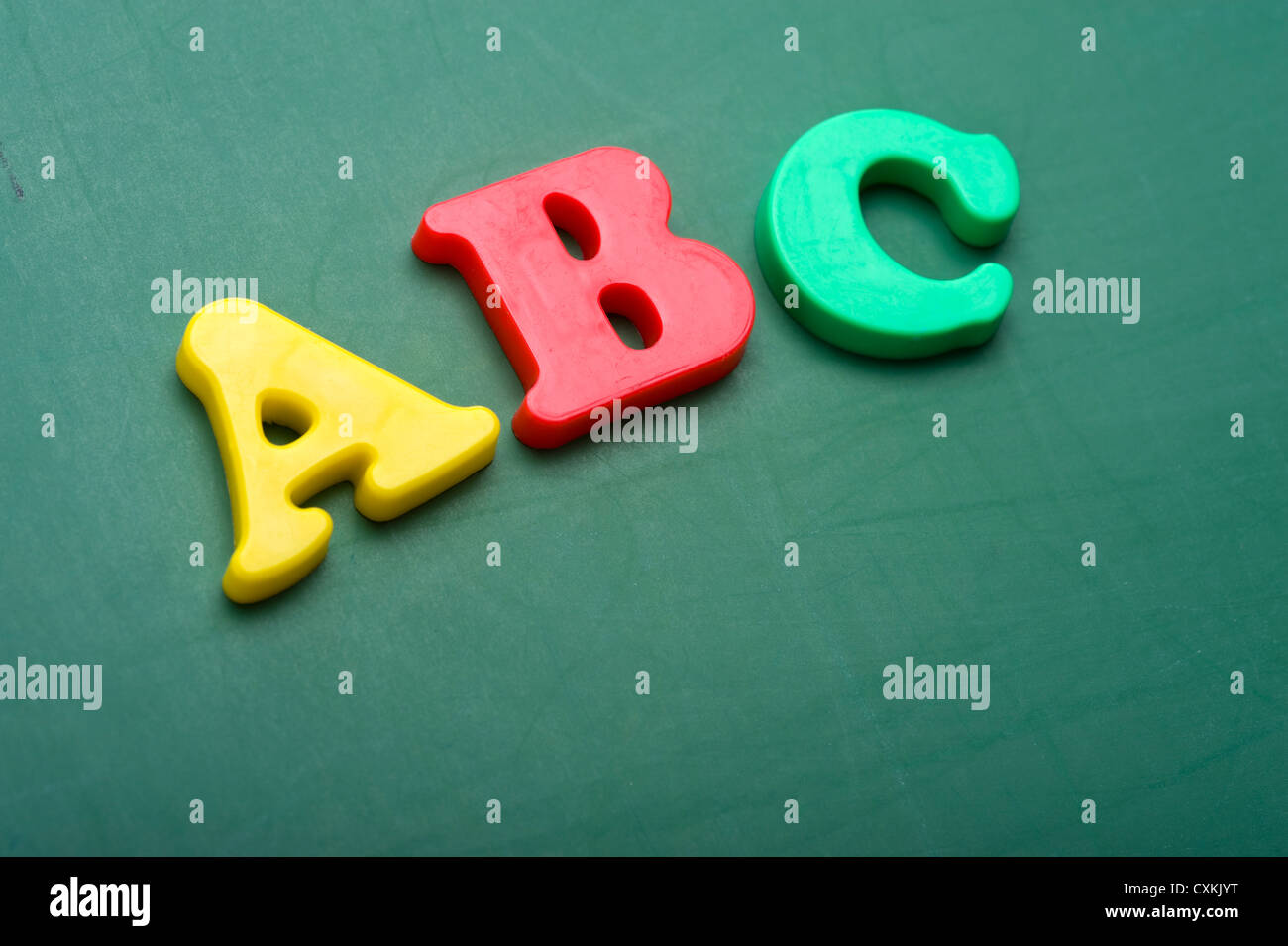 Kleine Kunststoff-Alphabet Buchstaben auf einer grünen Tafel mit Textfreiraum Stockfoto