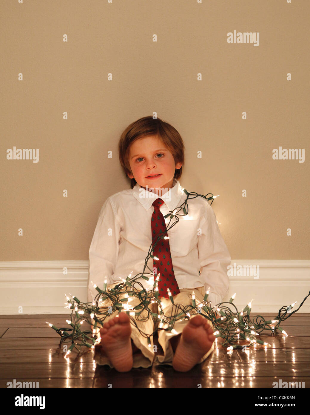 Kleiner Junge abgedeckt in Weihnachtsbeleuchtung Stockfoto