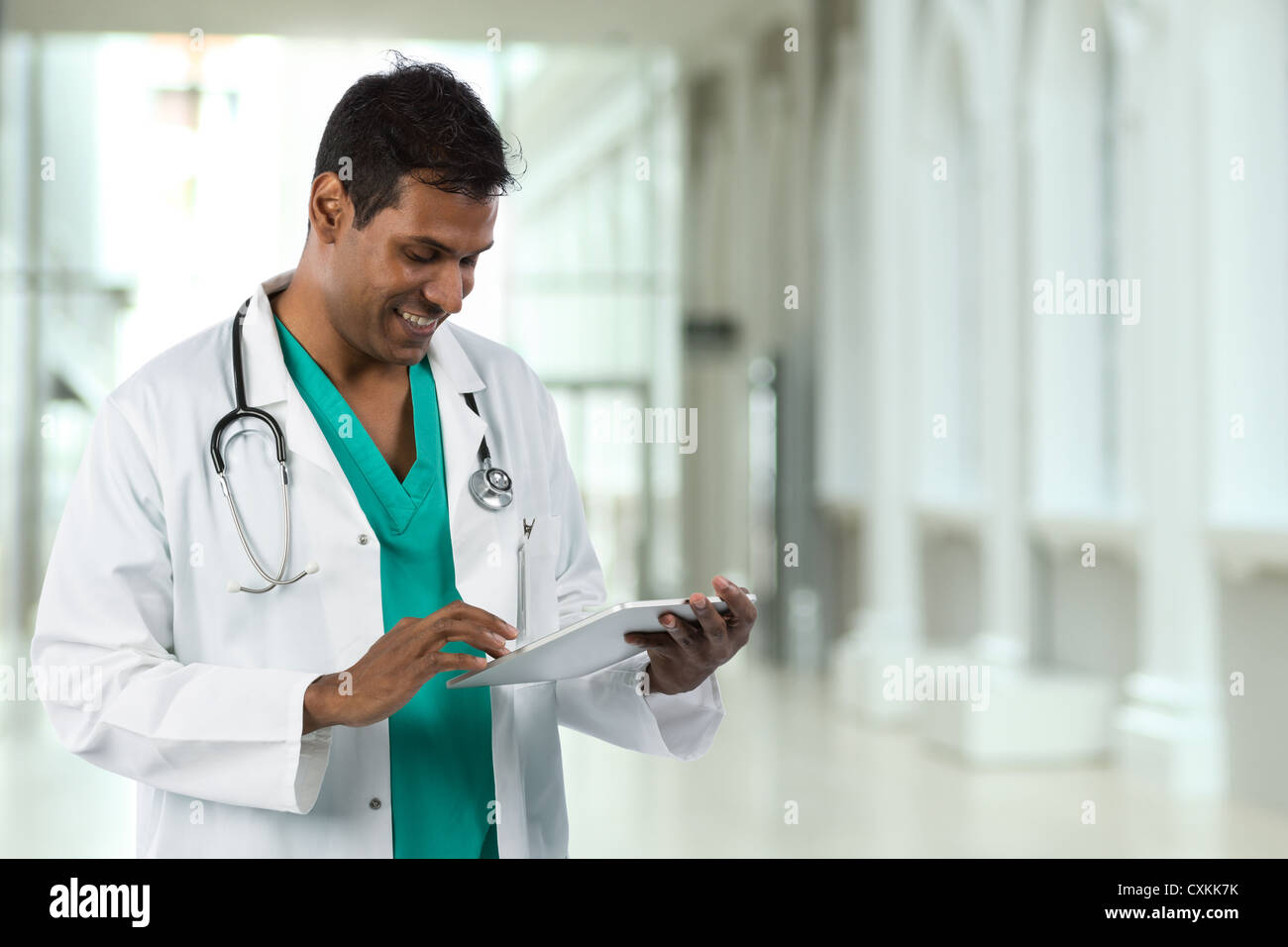 Männlicher indischer Arzt hält eine digitale-Tablette & stehen in einem Krankenhaus. Stockfoto