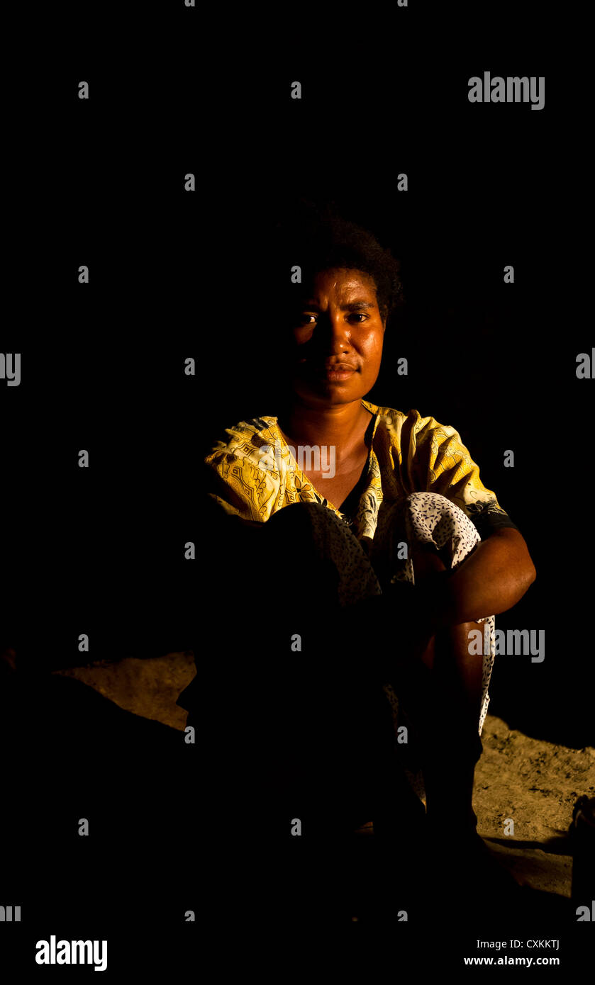 Junge Frau sitzt in einem traditionellen Haus nachts Erap, Papua New Guinea Stockfoto