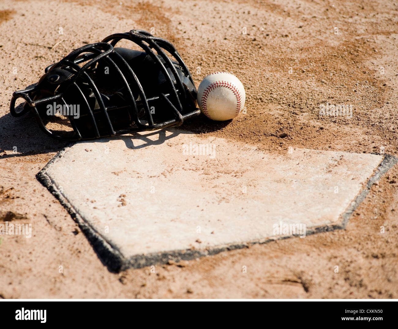 Einer Baseball-Catchers Schutzmaske und Baseball auf Home-Plate auf eine Schmutz-Baseball-Feld liegend Stockfoto