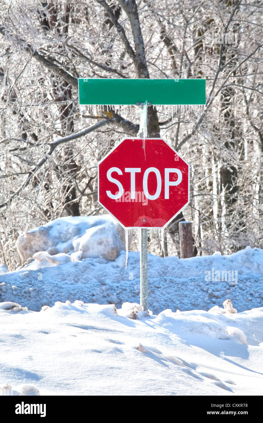 Stop-Schild in der Mitte von einem Snowbank und bedeckt im Eis und Eiszapfen. Stockfoto