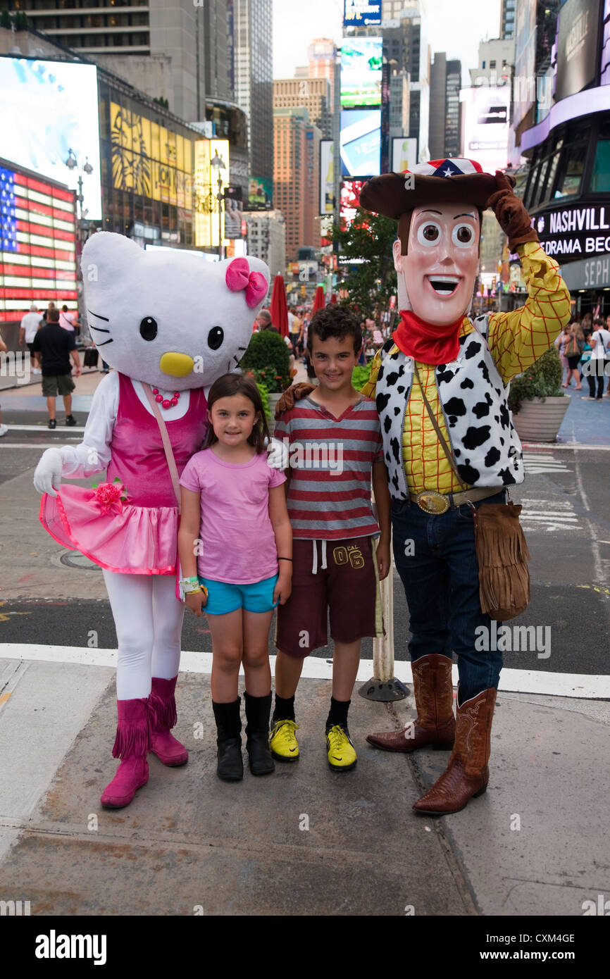 Kinder posieren für ein Foto mit Comic-Figuren Hello Kitty und Woody von Toy Story am Times Square, New York Stockfoto