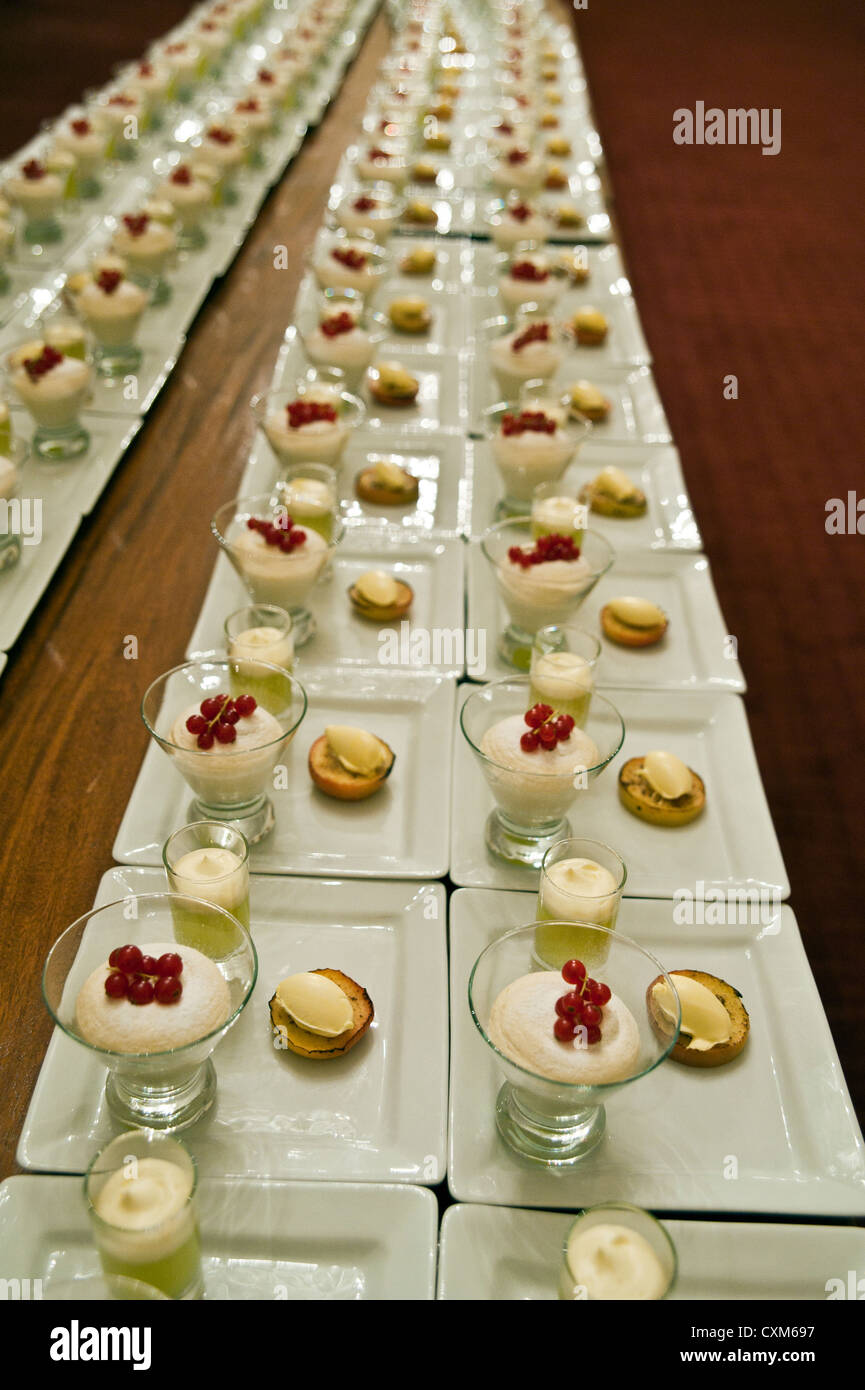 Tisch mit Reihen von identischen Pudding-Typ Pudding, vorbereitet für ein Bankett Abendessen gedeckt. Stockfoto