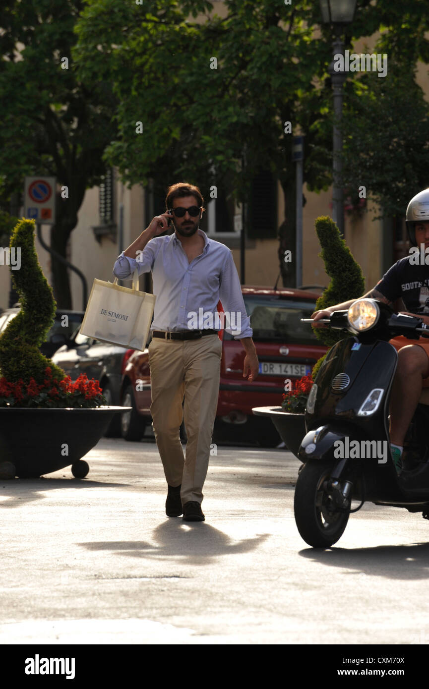 Modisch gekleideten jungen Mann, shoppen und telefonieren mit seinem Handy in Lucca Toskana Italien Stockfoto