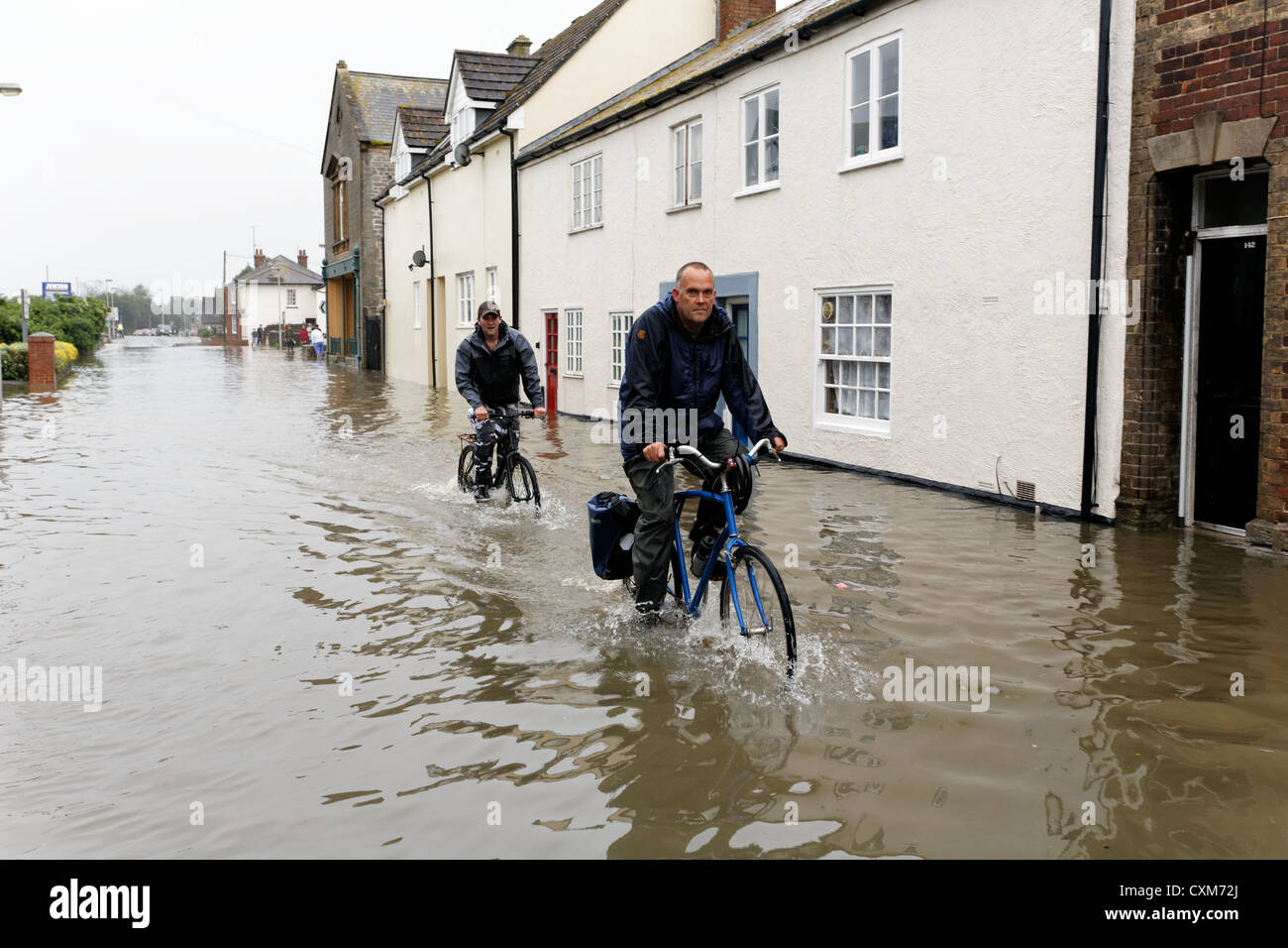 Radfahrer in South Street Bridport wo Häuser und Geschäfte nach starken Regenfällen überflutet wurden. Bridport Dorset UK Stockfoto