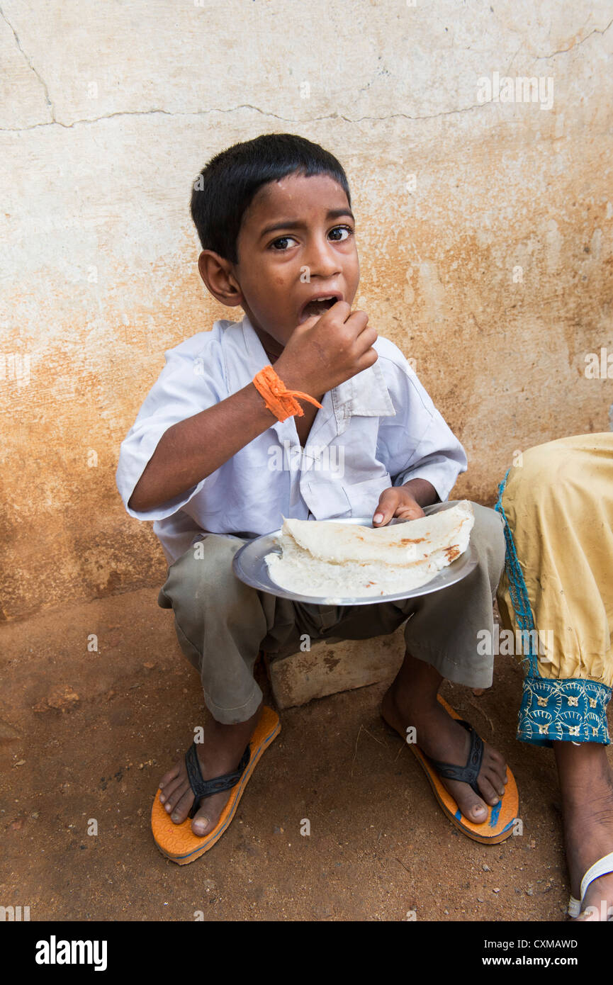 Niedrigere Kaste Indianerjunge Dosa zum Frühstück auf einer indischen Straße zu essen. Andhra Pradesh, Indien Stockfoto