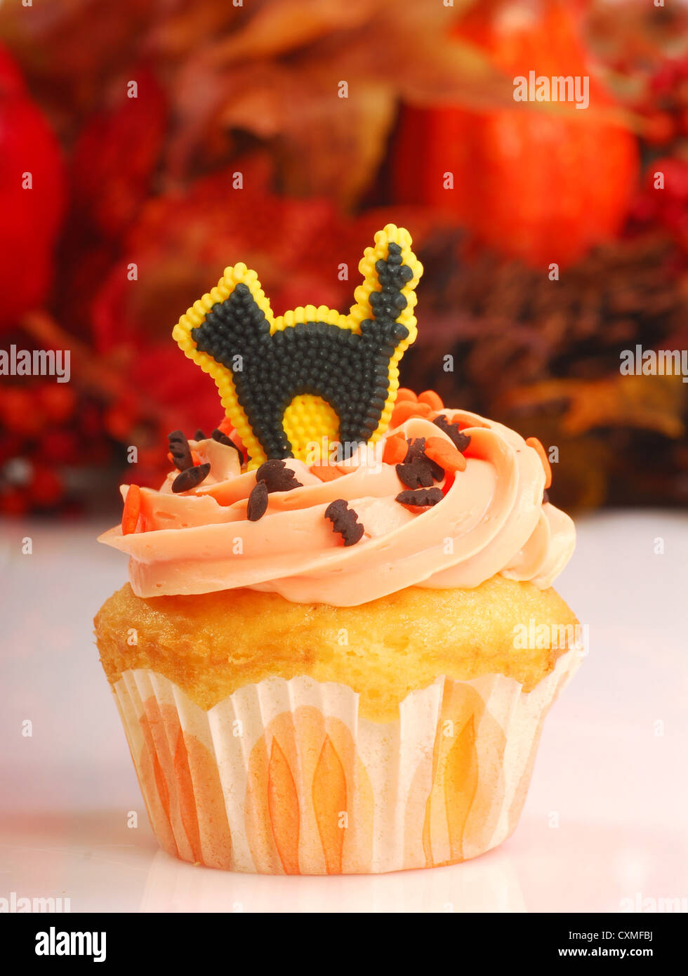 Köstliche Halloween Cupcake mit Buttercreme Zuckerguss und Herbstlaub im Hintergrund Stockfoto