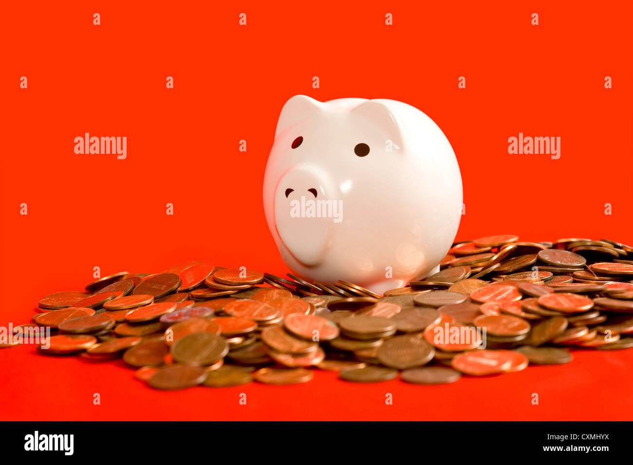 Ein weißes Sparschwein auf einem roten Hintergrund mit vielen amerikanischen Pfennige. Finanzkrise-Konzept Stockfoto