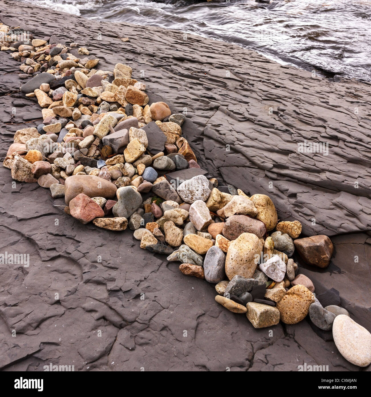 Linie der braunen Felsen und Kieselsteine auf einem schottischen Strand, UK Stockfoto