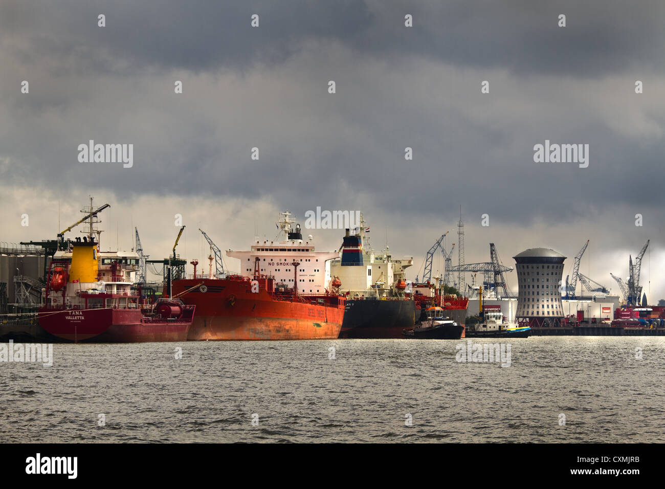 Tanker im Hafen mit Regenwolken, Sonnenschein und industriellen Hintergrund Stockfoto
