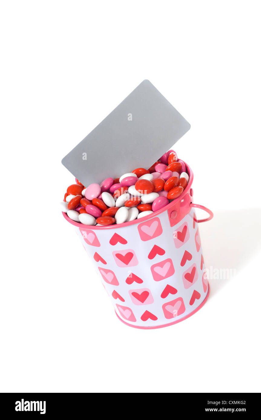 Einen Eimer voll von roten, weißen und rosa Bonbons mit einer leeren grauen Karte hinzufügen Nachricht mit textfreiraum auf weißem Hintergrund Stockfoto