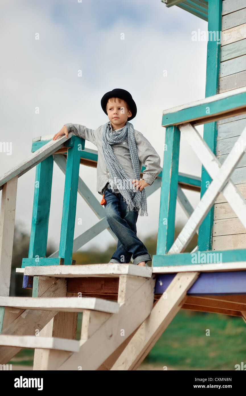 Stilvolle junge in einem Hut steht auf einer Holzbrücke auf dem Hintergrund des Meeres Stockfoto