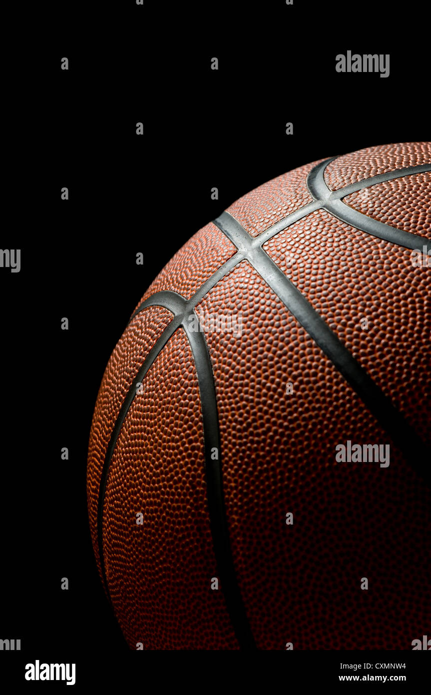 Brandneue Basketball auf schwarzem Hintergrund beleuchtet, von der Seite Stockfoto