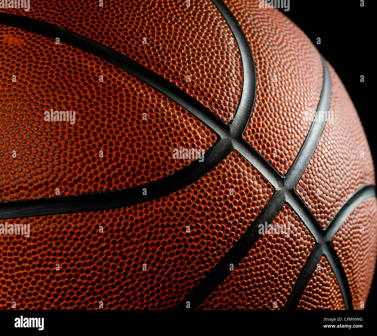 Brandneue Basketball auf schwarzem Hintergrund beleuchtet, von der Seite Stockfoto