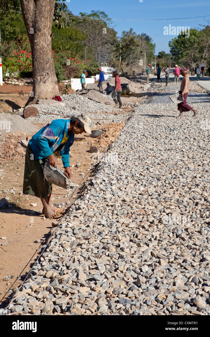 Myanmar, Burma, Shan-Staat. Arbeiter bauen eine asphaltierte Straße von Hand. Verlegung der Straße Bett aus Schotter. Stockfoto