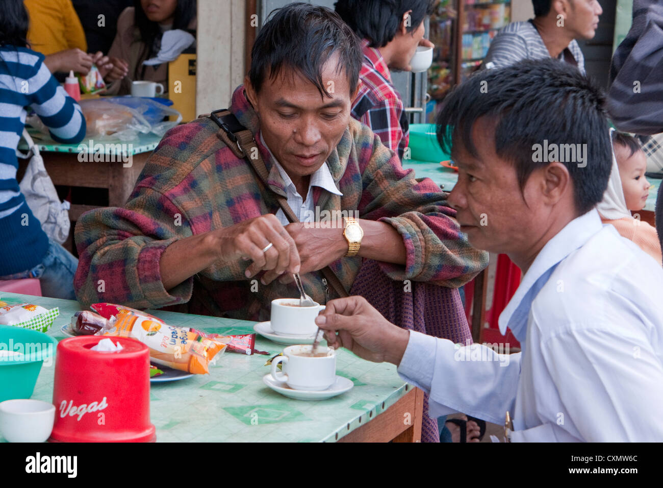 Myanmar, Burma, Shan-Staat. Zwei burmesische Männer Kaffeetrinken am Straßenrand Rast. Stockfoto