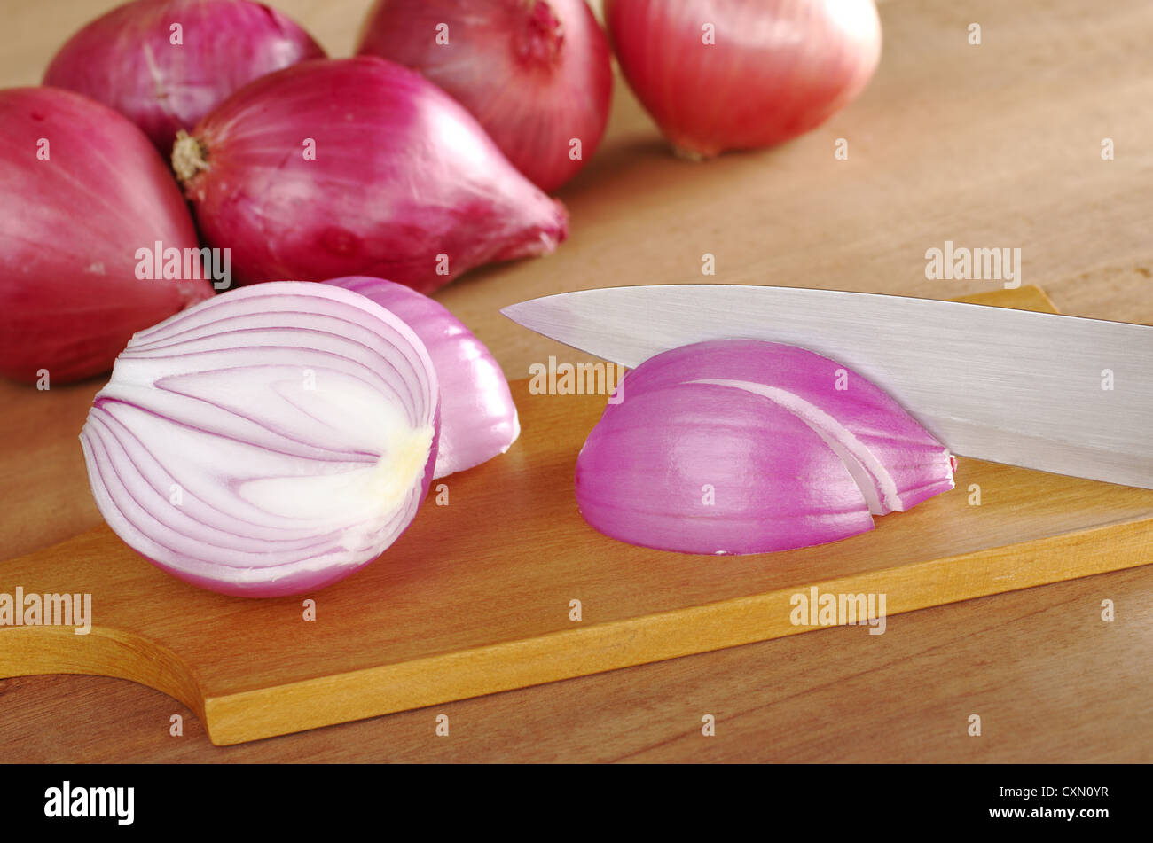 Schneiden rote Zwiebeln auf Holzbrett (selektiven Fokus, Fokus auf die geschnittene Zwiebel und das Messer) Stockfoto
