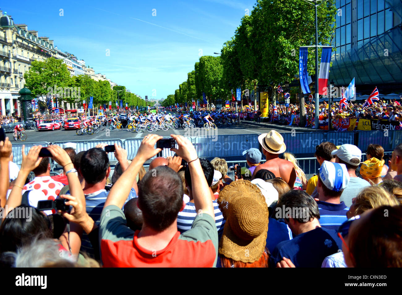 Die Tour de France-Hauptfeld rundet die Biegung an der Spitze der Champs-Élysées, während der riesigen Menschenmengen in der Aufregung nehmen. Stockfoto