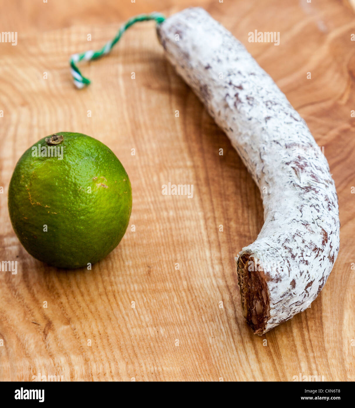 Ein Stück getrocknete französische Wurst und einer Limette auf einem Holzbrett. Stockfoto