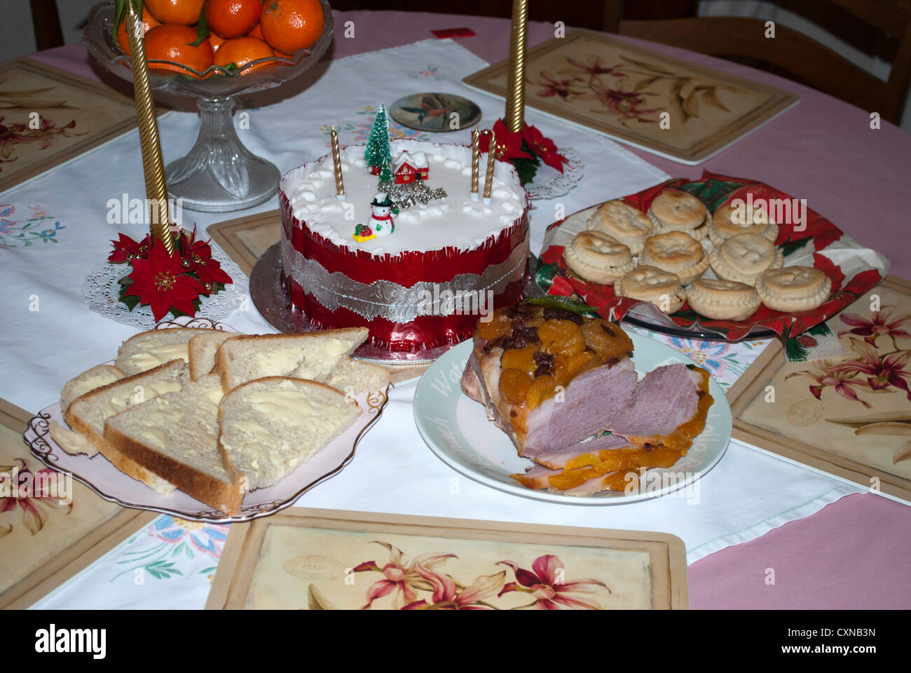 Nahrung für eine Weihnachtstee ausgebreitet auf dem Tisch eine Kleinigkeit, Weihnachtskuchen, in Scheiben geschnittenen Schinken, Brot und Butter, Mince Pies und Orangen Stockfoto