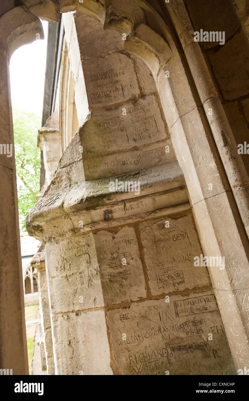 zerkratzte Namen von ehemaligen Schülern auf dem Stein rund um den Kreuzgang des Winchester college Stockfoto