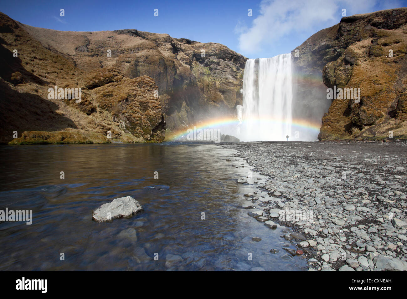 Die atemberaubenden Skogafoss Wasserfall in Island, mit Person unter einem bunten Wasserfall in den Schatten gestellt Stockfoto