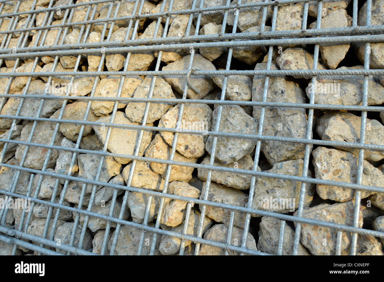 Recycelter, redundanter Beton, zerkleinert, um eine Art Gabion-Käfigkorb in einer Stützwand hinter einem verzinkten Stahlgeflecht zu bilden East London England Großbritannien Stockfoto