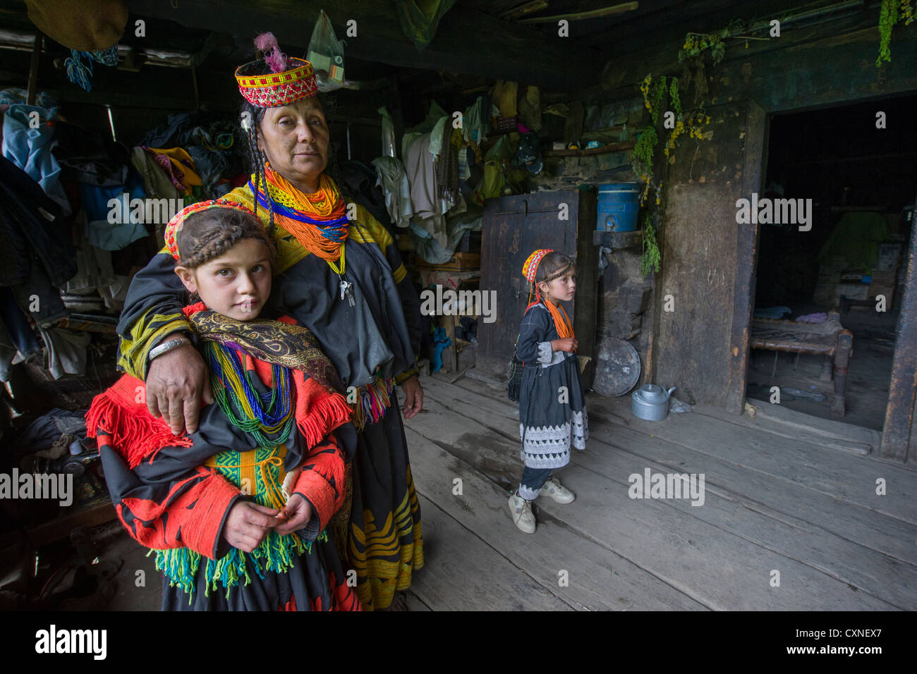 Kalash Mutter und ihre Kinder auf der Veranda des ältesten Hauses im Tal, Kalasha Grum Dorf, Rumbur Tal, Chitral, Khyber-Pakhtunkhwa, Pakistan Stockfoto