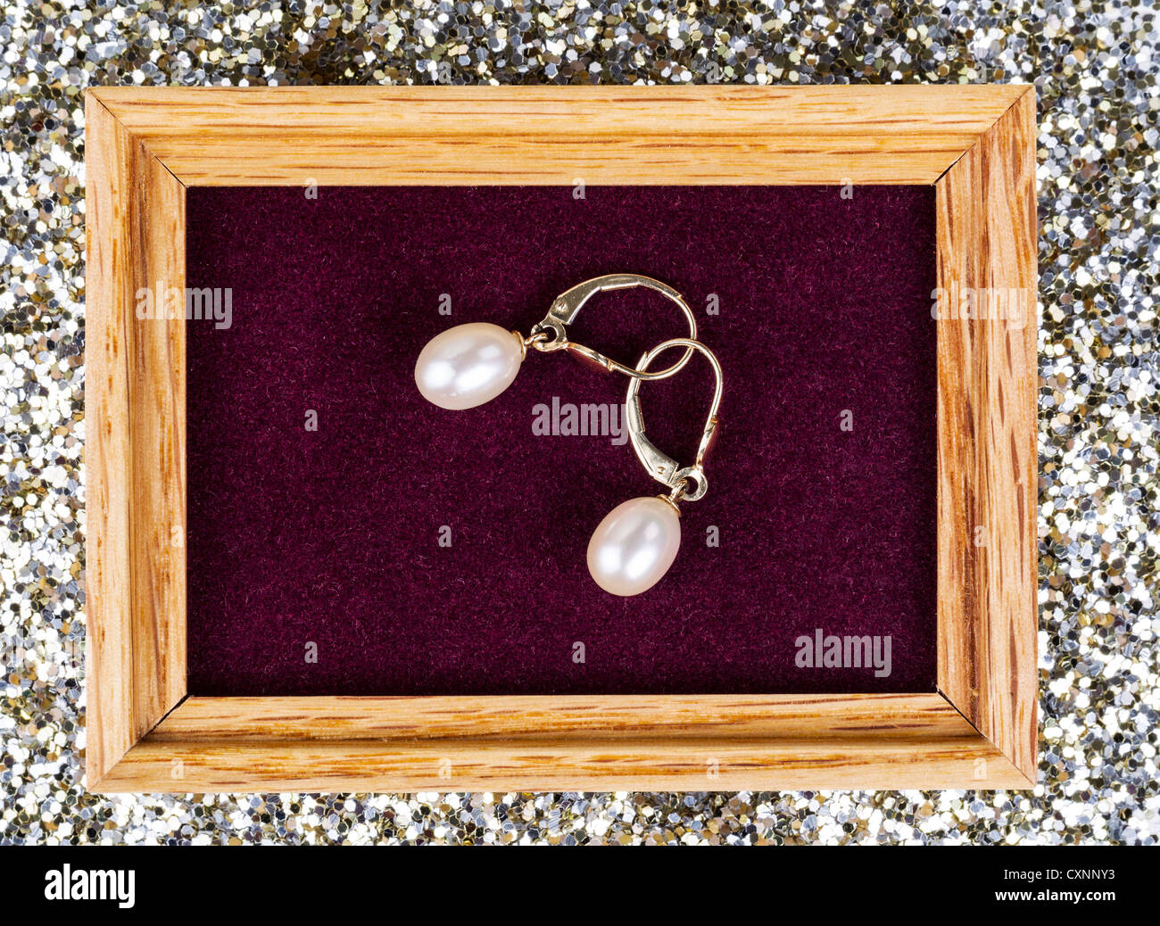 Goldene Perle Ohrringe in Schmuck-Box mit Glitter im Hintergrund Stockfoto