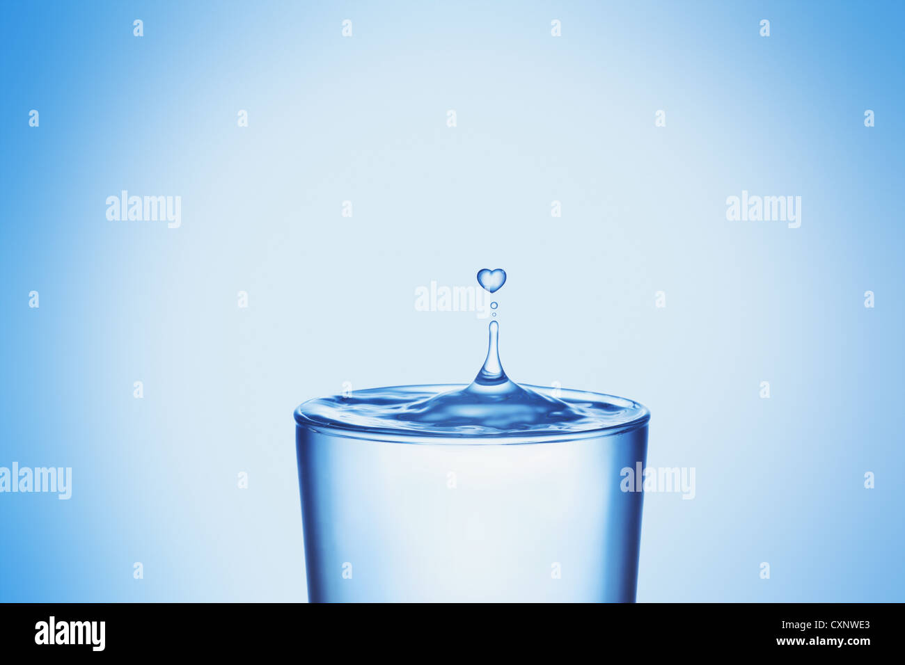 Wassertropfen planschen im Glas in Herzform Stockfoto