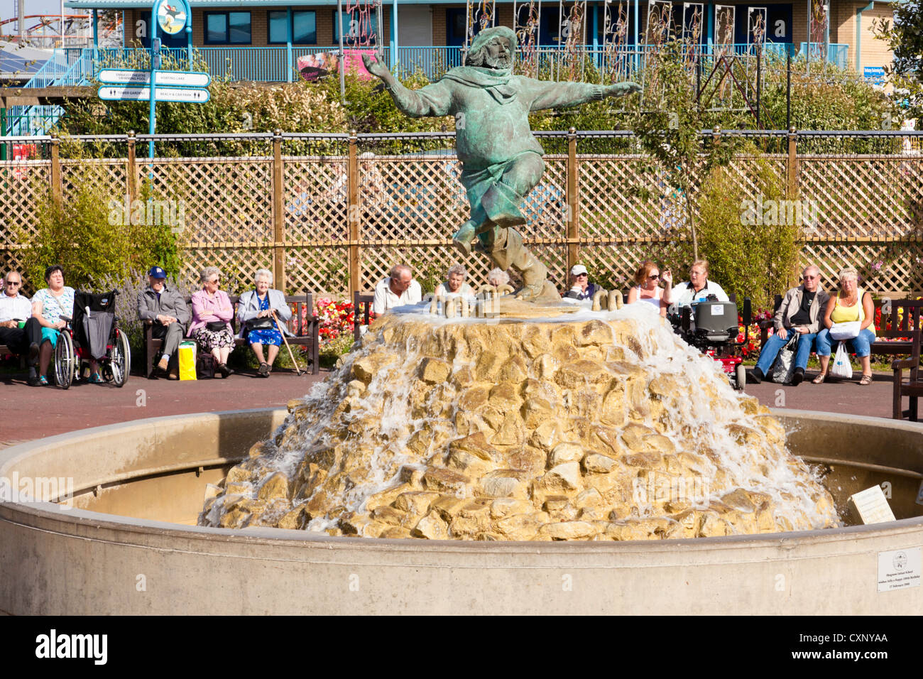 Urlauber, die herumsitzen und der Jolly Fischer Skulptur in Skegness, Lincolnshire, England, UK Stockfoto