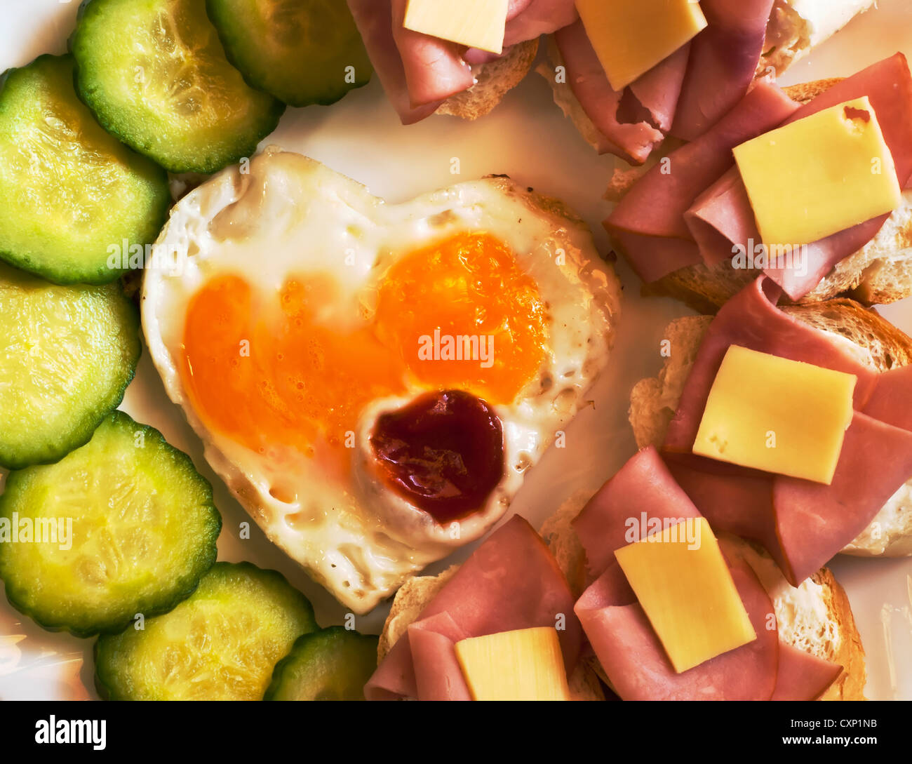 Gebratenes Ei auf herzförmigen - Toast mit Gurke und Schinken zum Valentinstag Stockfoto