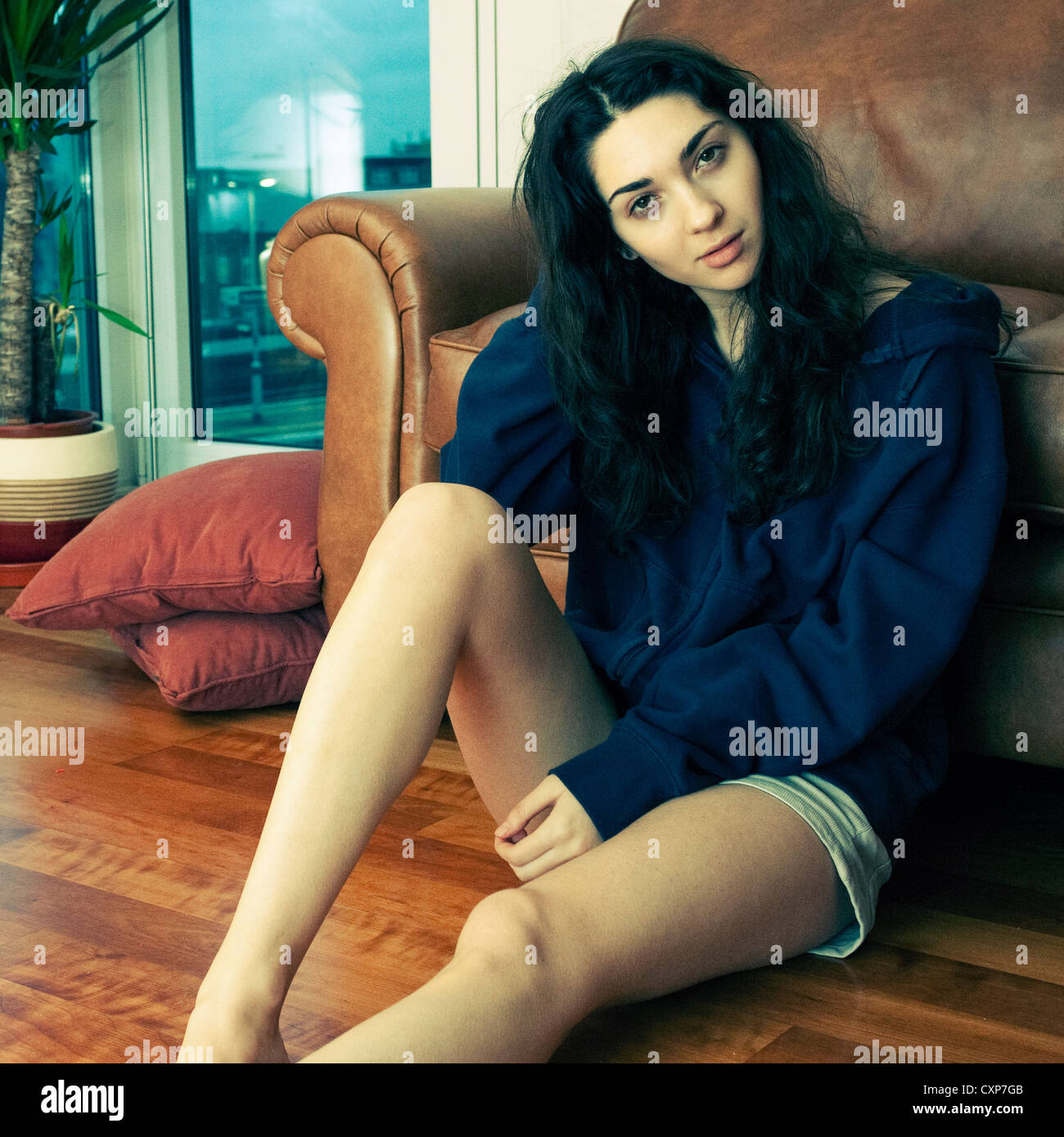 Junge Frau sitzt auf dem Boden zu Hause Stockfoto