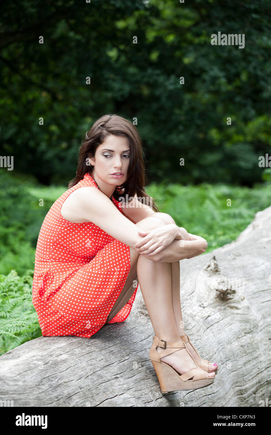 Junge Frau sitzt auf dem Baumstamm denken Stockfoto