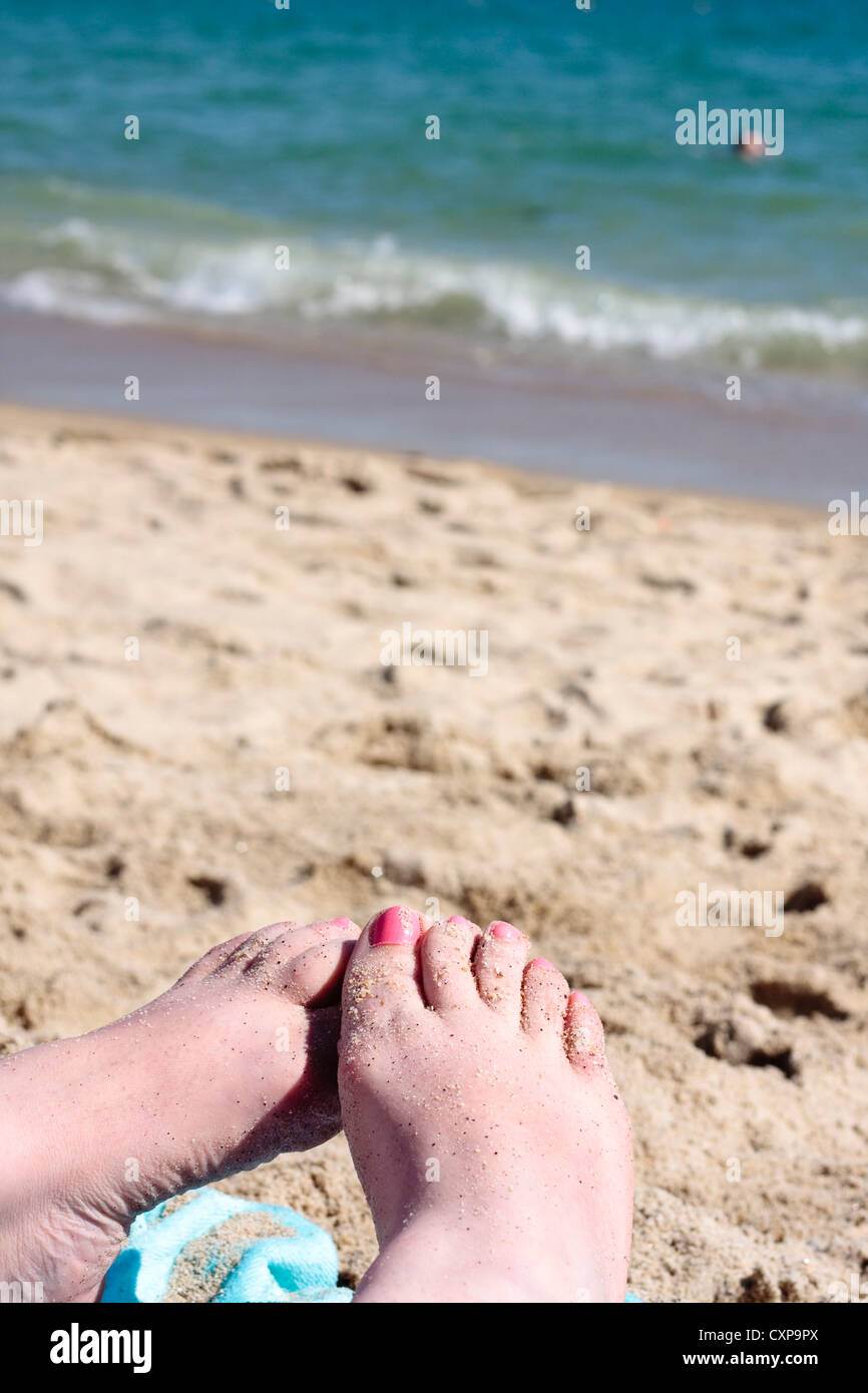 Sand abgedeckt weiblicher Füße am Strand Stockfoto