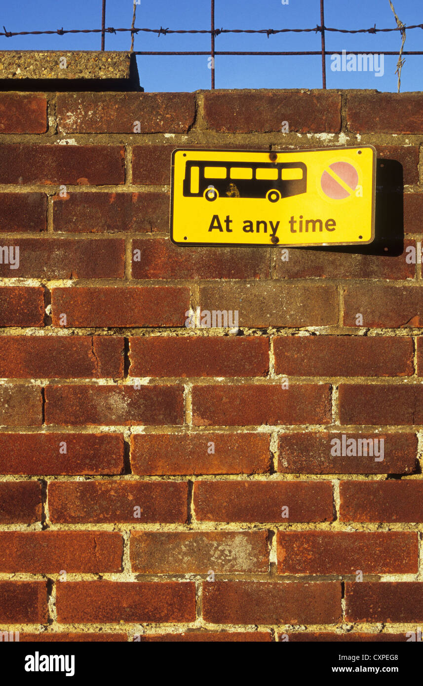 Mauer mit Stacheldraht unter blauem Himmel und gebogenen gelbes Schild besagt Nein warten auf Busse, zu jeder Zeit vernachlässigt Stockfoto