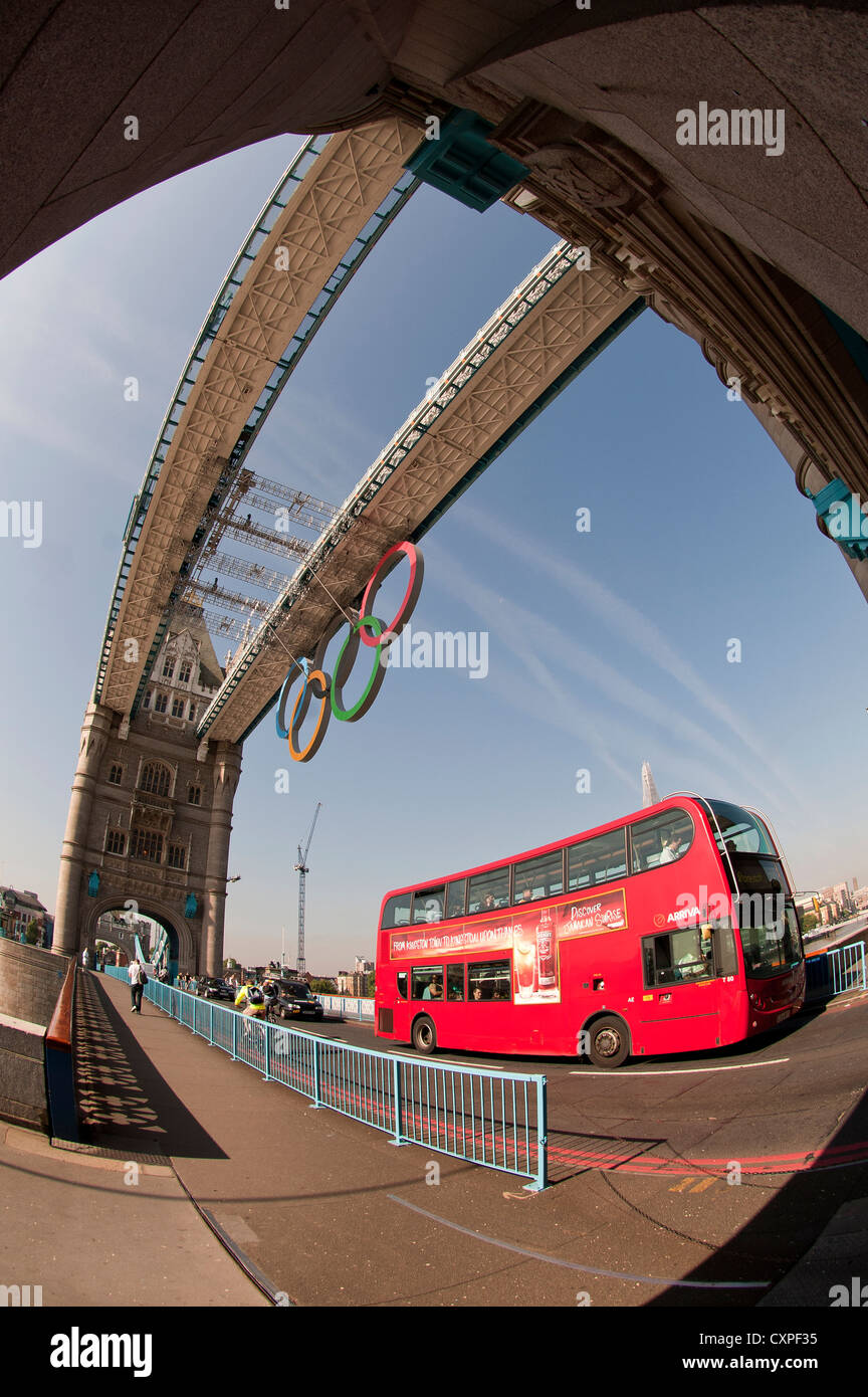 Ein roter London Doppeldecker bus über Tower Brücke unter den Olympischen Ringen. Stockfoto