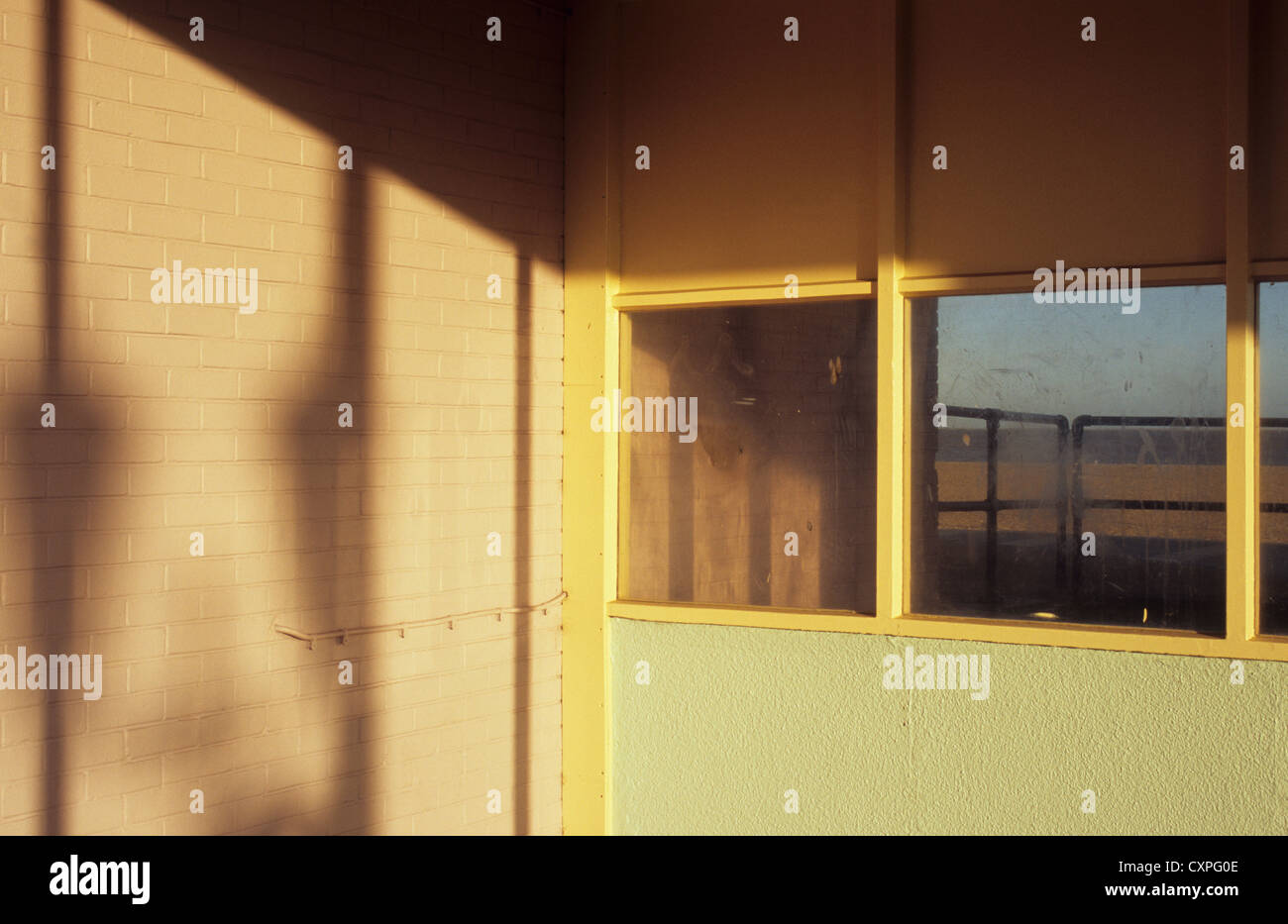 Meer Unterkunft in warmes Licht mit Schatten Fenster und Blick über schmutzigen Glas Geländer Strand Meer und Himmel Stockfoto