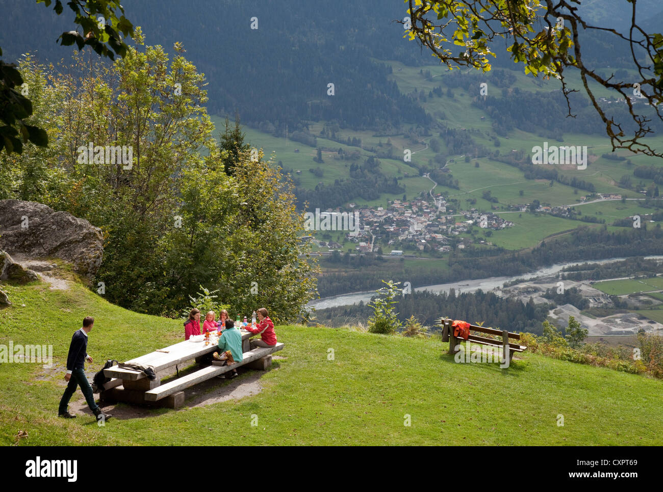 Rhein Schweiz; Eine Familie bei einem Picknick mit Blick auf ein Tal, in dem der Oberrhein im Sommer fließt, Falera, Graubünden, Schweiz Stockfoto