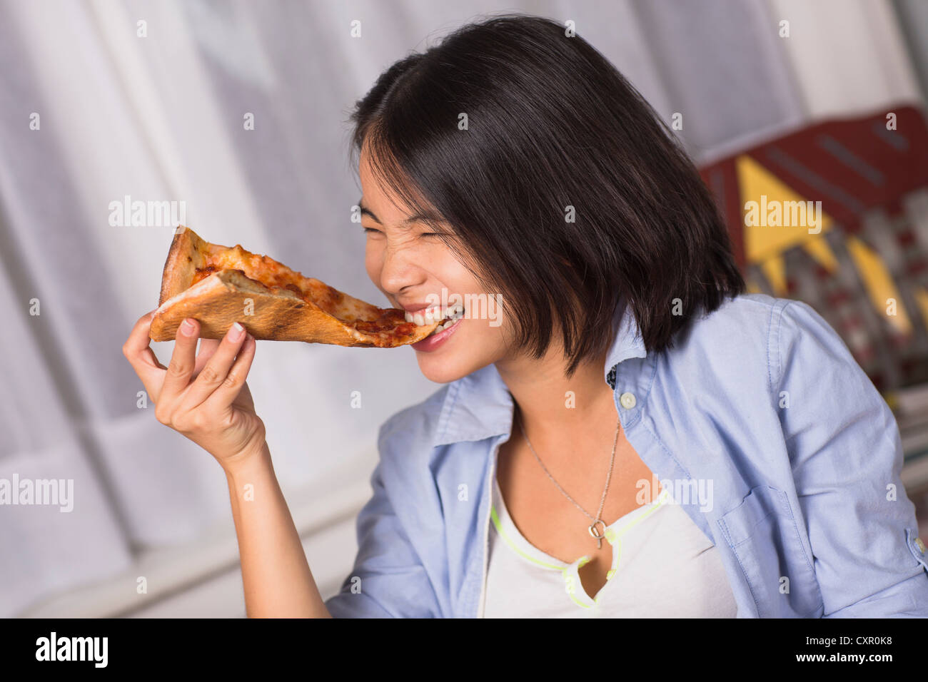 Junge Frau beißt ein Stück pizza Stockfoto