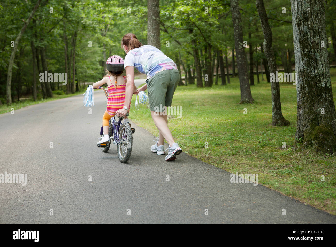Tochter der Mutter helfen, Fahrrad fahren Stockfoto