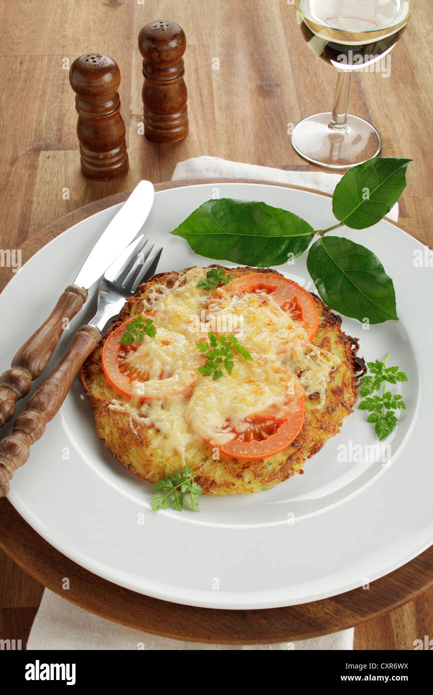 Kartoffel-Rösti mit Scheiben von Tomaten und geschmolzenem Käse, Weißwein Stockfoto