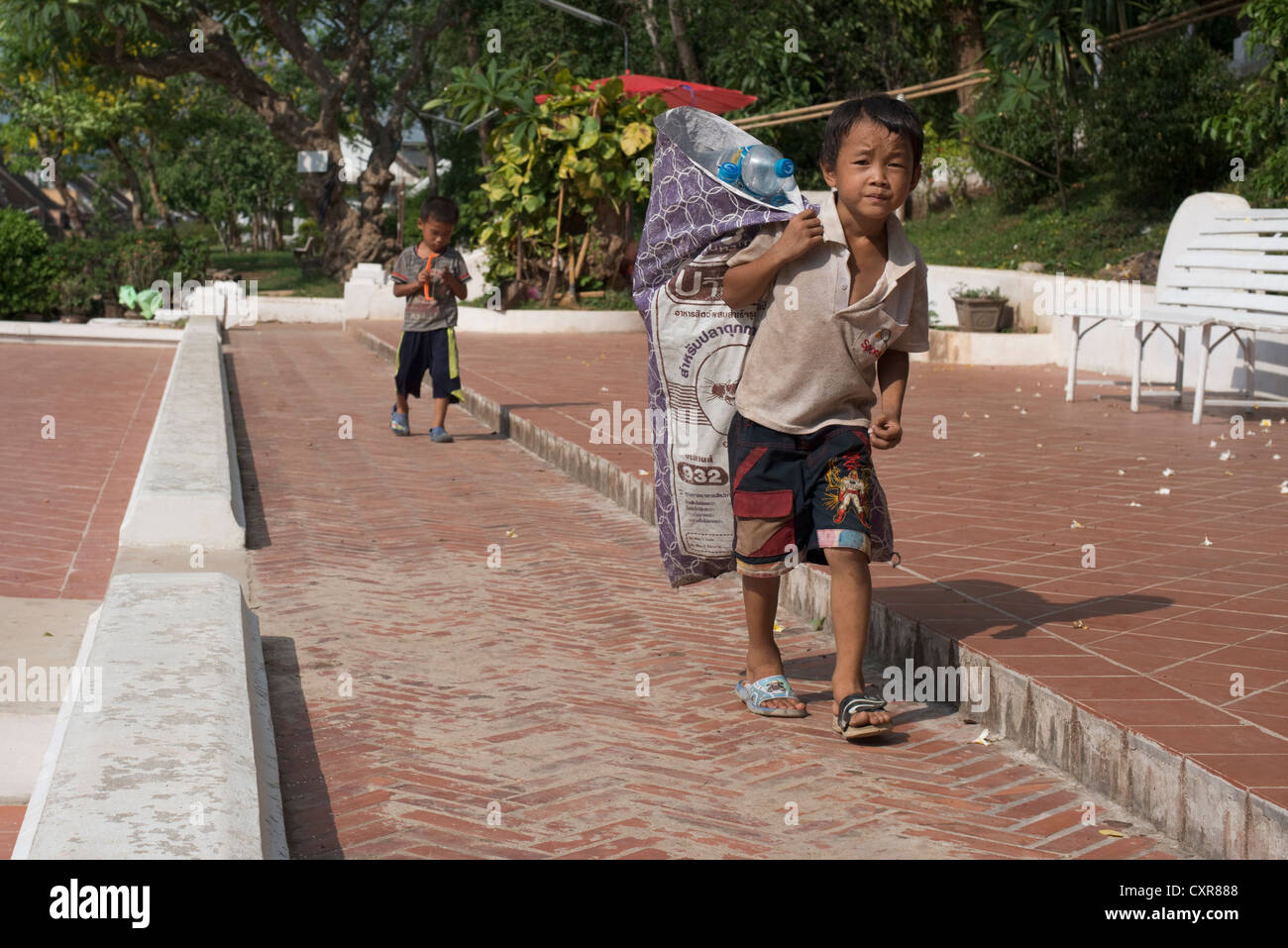 Ein Junge trägt eine Plünderung Kunststoff-Flaschen, die er gesammelt hat, um für das recycling zu verkaufen. Luang Prabang, Laos Stockfoto