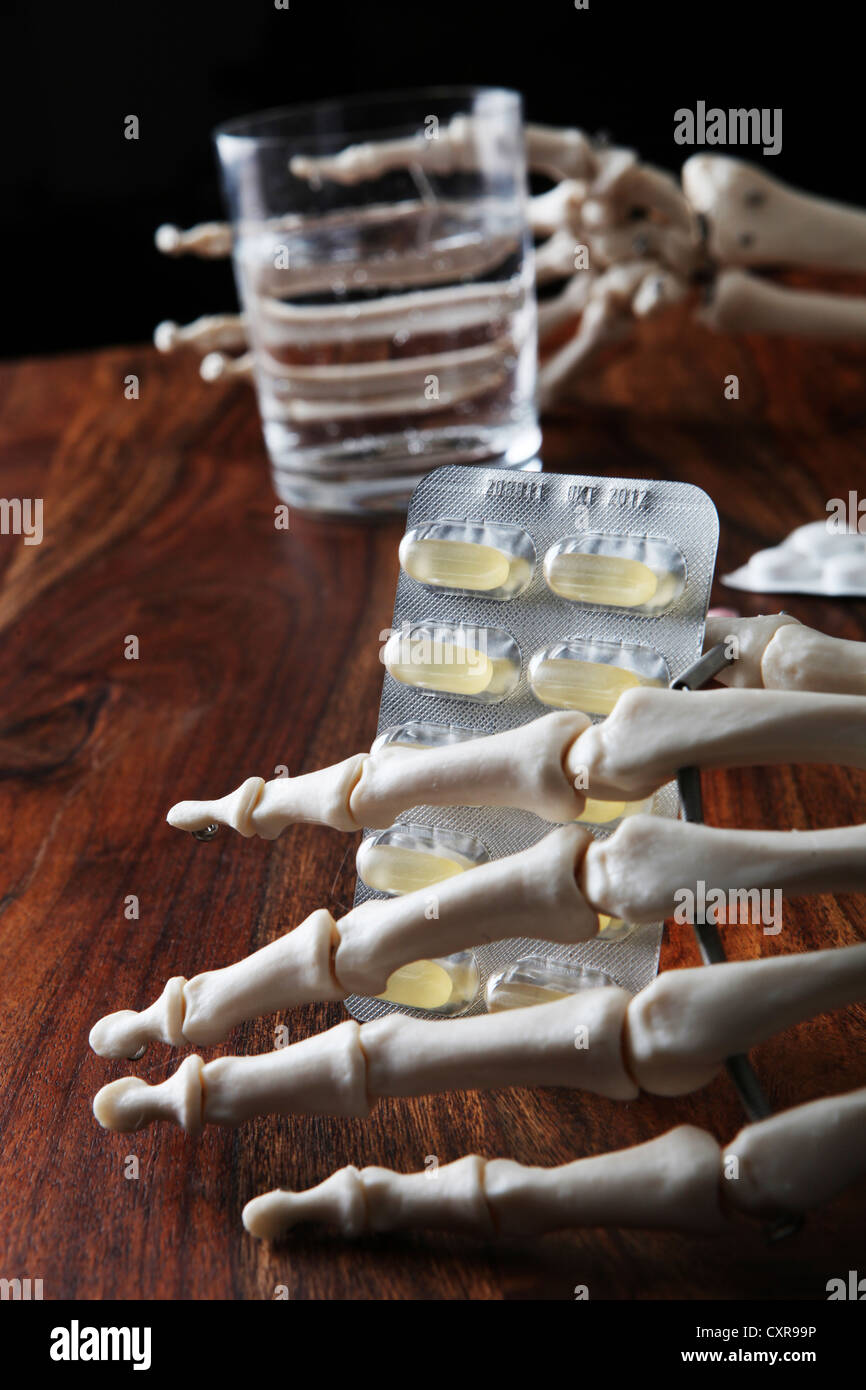 Skelett mit Tabletten und ein Glas Wasser in seine knöcherne Hand Stockfoto