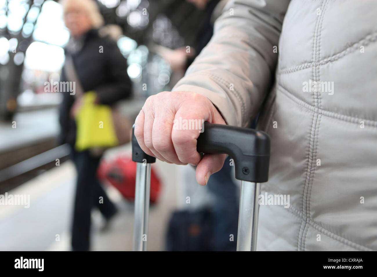 Hand auf den Griff eines Koffers, warten Passagiere am Kölner Hauptbahnhof, Köln, Nordrhein-Westfalen Stockfoto